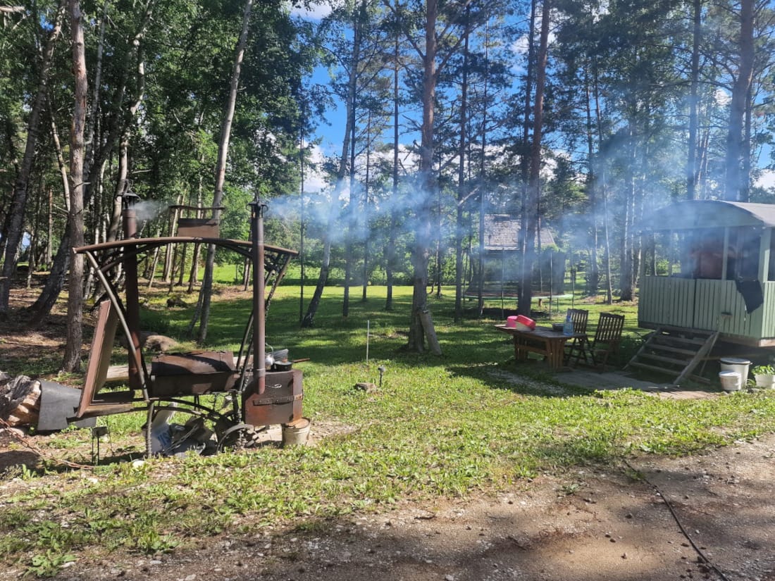 vihreän vankkurin edessä on rautainen grilli, jonka liedellä kahvipannu ja kattaila