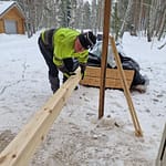 Mies siirtää lautapinosta lautoja sisälle