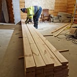 Mies asettaa lautaa pinoon rakennuksessa, jossa ikkunat peitetty lastulevyllä