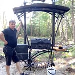 Mies seisoo koristeellisen grillin vieressä