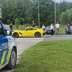 poliisivalvoo Keltainen auto ajaa tiellä. Poliisiauto valvoo liikennettä keula tielle päin