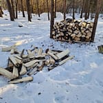 Puu pino, jonka edessä pinoamattomia klapeja maassa