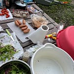 ruskealla terassipöydällä salaattikulho, talouspaperirulla ja grillimakkaroita