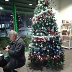 Mies istuu kahvilan pöydässä joulukuusen edessä