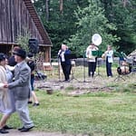 Soittokunta soittaa ja vanhanaikaisesti pukeutunut tanssipari tanssii