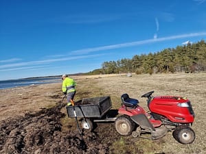 Punainen puutarhatraktori rannalla leväkasan vieressä