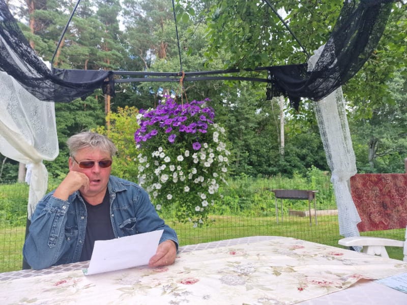 Mies lukee ruokalistaa vihreällä pihalla